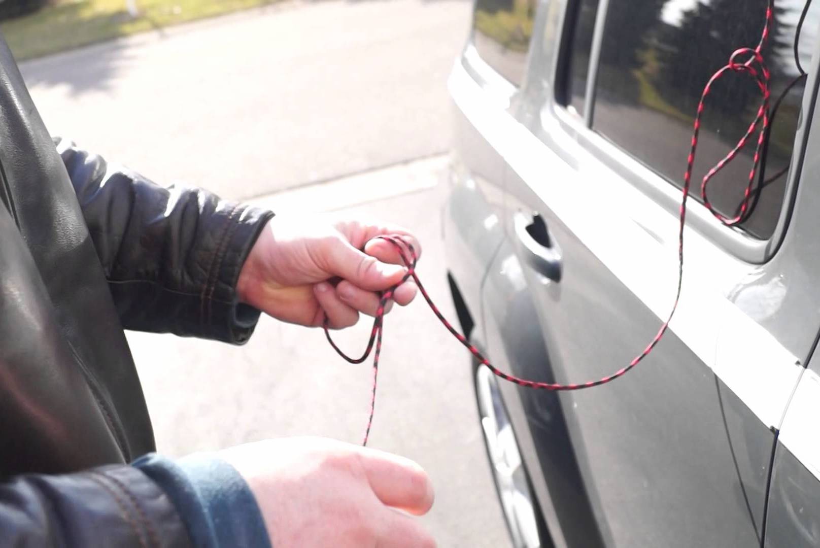 Locksmith performing an emergency car door unlocking service in a parking area