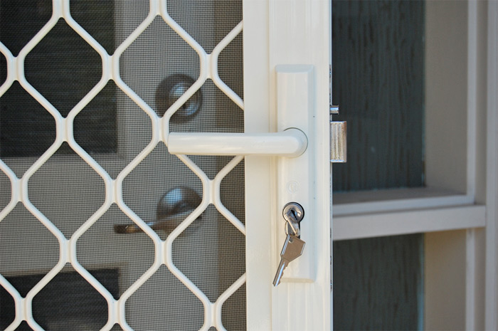 Locksmith repairing a metal security grille lock on an apartment entrance